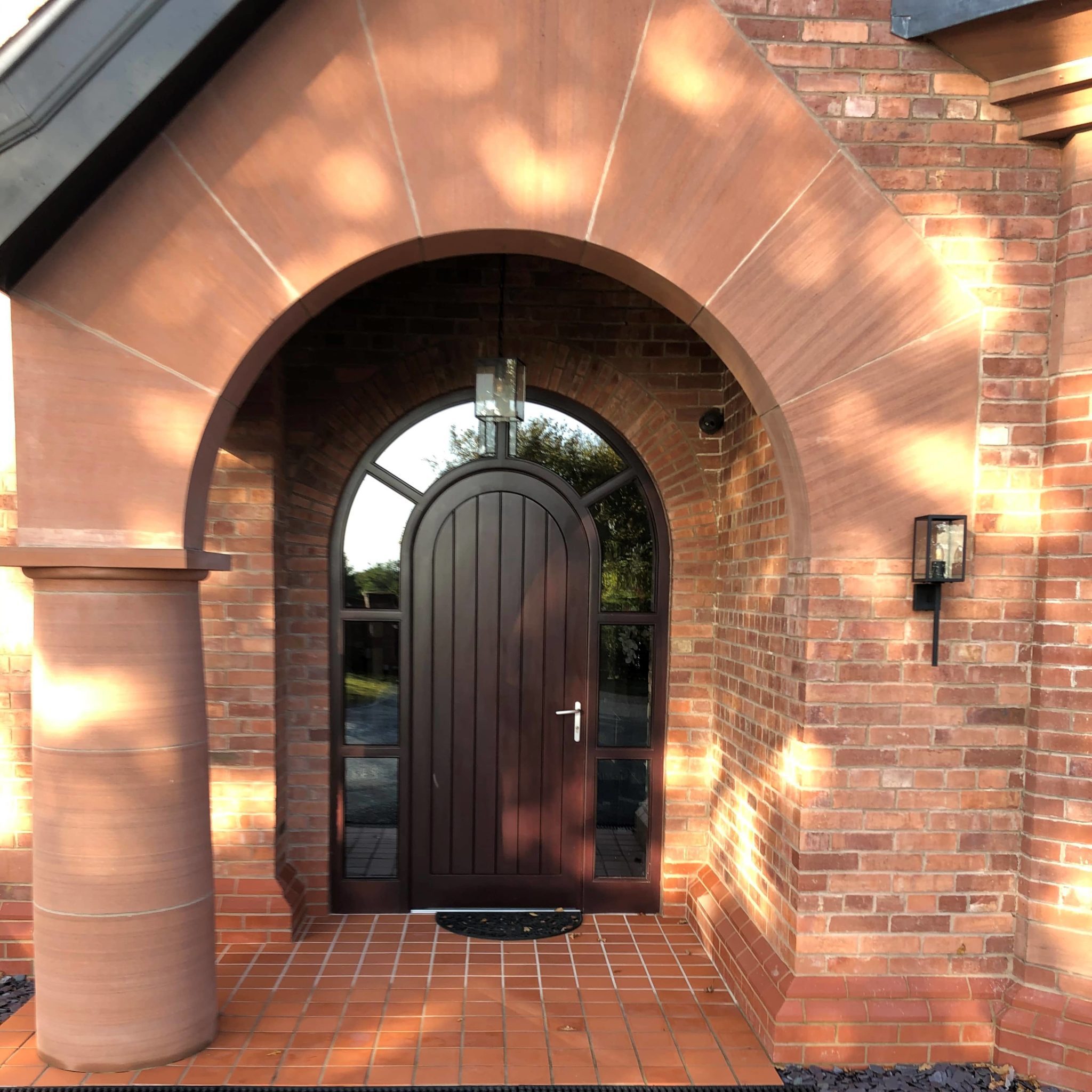 a brick house with a brown door and arched doorway.